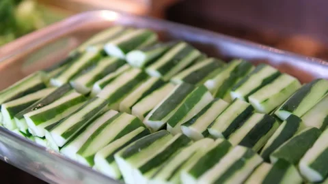 Close-up of sliced cucumbers on a white plate, served in a rustic wooden Stock Footage 310160308