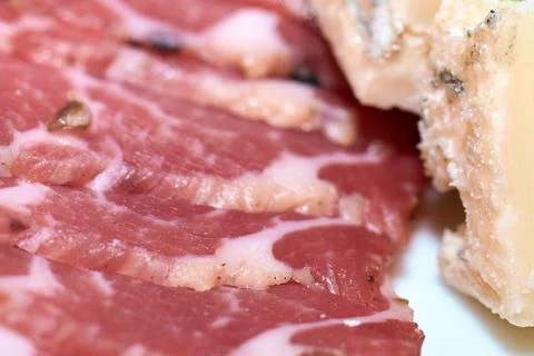 Close-up of sliced cured meat with appetizing texture and gourmet cheese piec Stock Photos