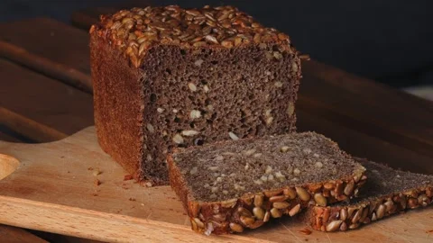 Close up of sliced dark bread with sunflower seeds on top on wooden cutting.. Stock Footage 313552998