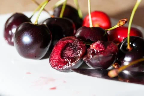 Close-up of sliced dark red cherry with glossy juicy flesh, visible pit cavity, Stock Photos