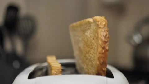 Close-up of sliced fried white bread flying out of an electric toaster in slow Stock Footage 220910752
