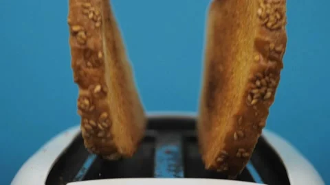 Close-up of sliced fried white bread flying out of an electric toaster in slow Stock Footage 234997312