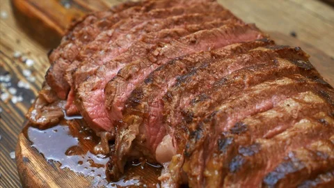 Close Up of Sliced Grilled Meat Beef Steak with Spices on Wooden Cutting Board Stock Footage 120253766