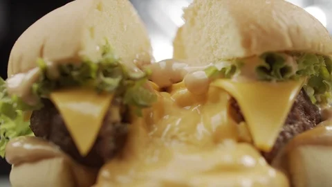 Close-up of sliced juicy burger from which cheese in slow motion flows Stock Footage 120512591
