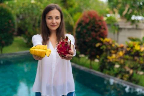 Close-up sliced mango and dragon fruit (pitaya) in hands of blurred girl on Foto stock