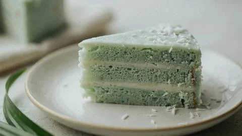 Close-up of a sliced matcha layer cake topped with white coconut frosting on a Stock Photos