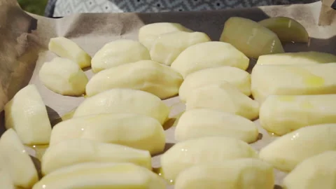 Close-up of sliced potatoes on a baking sheet lined with baking paper. Video stock 317932866