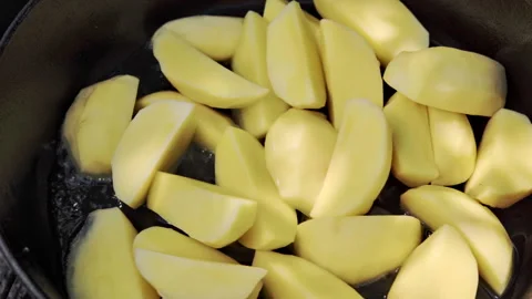 Close-up of sliced potatoes being roasted in a cast iron pan on the grill. Video stock 315269405