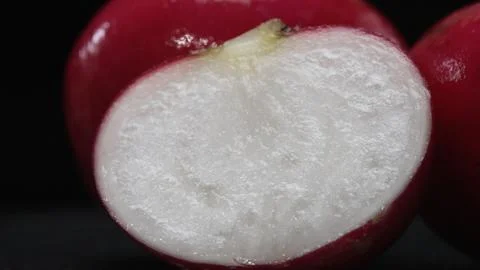 A close-up of a sliced radish explodes against a black background. Comestible. Foto stock
