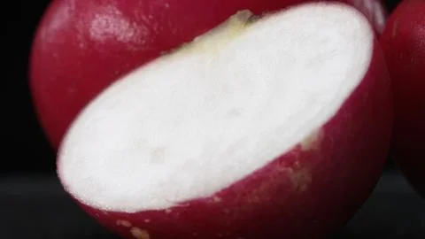 A close-up of a sliced radish explodes against a black background. Comestible. Foto stock