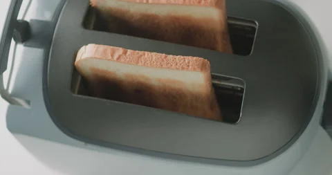 Close up of sliced roasted white bread popping from electric toaster. Kitchen Stock Footage 221231969