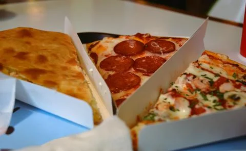 Close-up of slices of different types of pizza in white triangular containers Foto stock