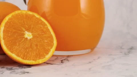 Close up of slices of orange next to jug with fresh orange juice 動画素材 130880586