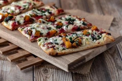 Close up of slices of root vegetable flat bread pizza ready for eating. Stock Photos