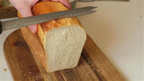 Close-up of  slicing a freshwhite bread loaf with a bread knife Stock Footage 341461671
