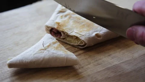 Close-up of Slicing a Grilled Lavash Wrap with Ham and Melted Cheese Stock Footage 331994142