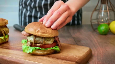 Close-up slicing in half a beef burger on the table and serving in 4K. Stock Footage 153762650