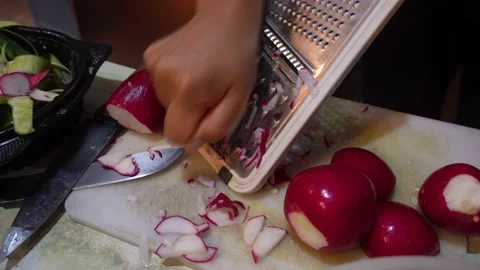 Close up slicing a radish with hands on a manual slicer Stock Footage 145998579