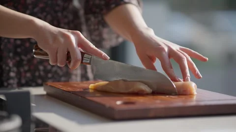Close Up of Slicing Raw Chicken Breast on Wooden Cutting Board Stock Footage 336466819