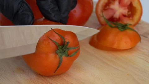 Close up, slicing tomato on the chopping block and preparing them. Видео 136820455