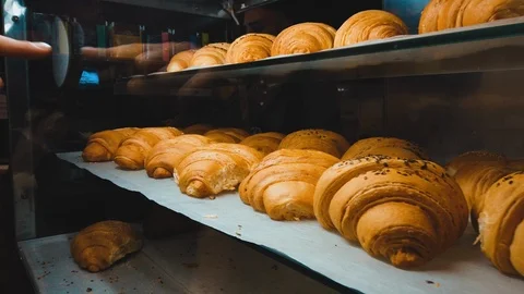 Close-up slide view on a croissant display case indoor. Female hand choosing cro Video stock 118993644