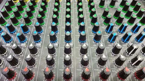 Close-up sliders, buttons and knobs of audio mixer in broadcast studio. Stock Photos