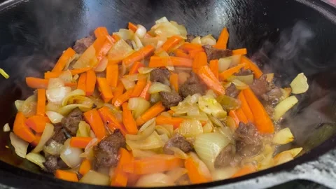 Close-up of a slotted spoon stirring meat, carrots and onions Stock Footage 278601200