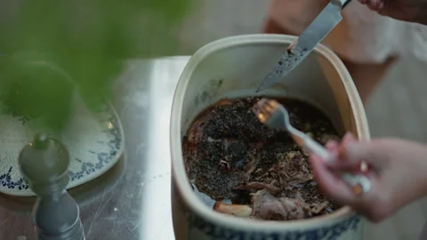 Close up of slow cooked shredded meat in ceramic dish beside spoon on stainless Stock Footage 345270306