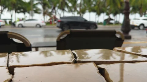 Close up slow motion 120fps of rain drops on stone curb in outdoor cafe near Vidéo 345101339
