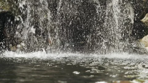 Close-up slow motion 120fps of a waterfall stream falling into a lake. Calm Stock Footage 297040122