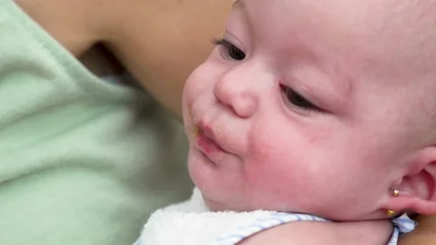 Close-up slow-motion 4K video of a mother feeding her baby a fruit puree, beg Stock Footage 220880020