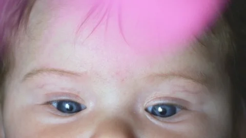 Close-up in slow motion of baby's beautiful blue eyes with moving toy Stock Footage 114104171