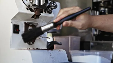 Close-up slow motion of barista brushing coffee grinder chute and burrs Stock Footage 332606379