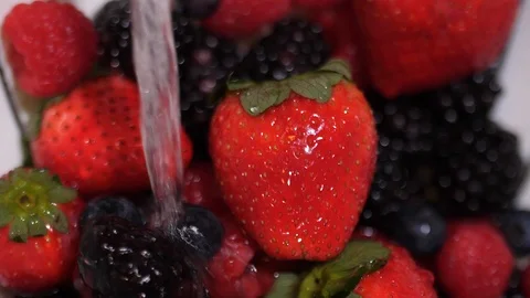 Close up slow motion berries being washed with a side to side water stream. Video stock 86536193