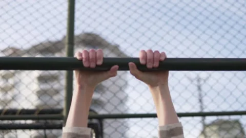 Close-up, slow motion, Blond boy pulling up on the bar on the street. Stock Footage 241407155