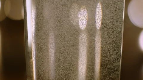 Close Up Slow Motion Bubbles Swirling in a Glass with Warm Bokeh Background Video stock 129396331