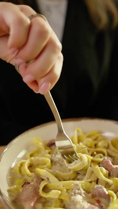 Close-up slow motion capturing female hand twirling spaghetti around fork Video stock 301372147