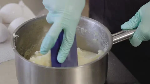 Close-up, Slow Motion, Chef's Hand in Glove Stirs Cream Mass Cooked in Metal Bar Video stock 136779009