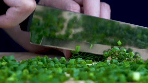 Close up slow-motion chopping Spring onion in straight view, focus at the knife Видео 136351782