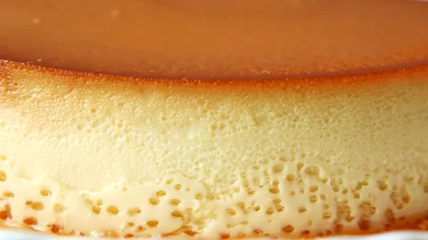 Close up slow motion of delicious caramel custard pudding on white plate ba.. Stockbeeldmateriaal 332579577