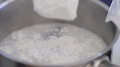 Close-up, Slow Motion, Dry Cake Cream Poured into Boiling Water in Metal Bar Stock Footage 136798832