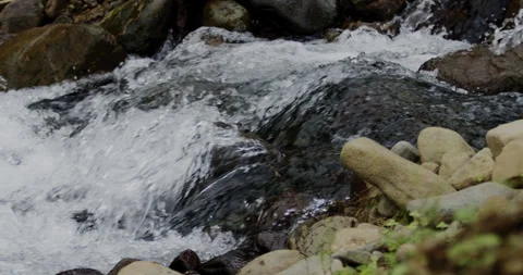 Close Up Slow Motion Flowing River Water with Rocky Shore Stockbeeldmateriaal 336806249