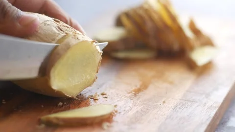 Close up slow motion footage of hand slicing ginger root on wooden cutting .. Stock Footage 332626270