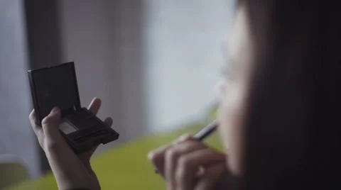 Close-up slow motion footage how woman holds a small mirror to do a makeup Stock Footage 61337021