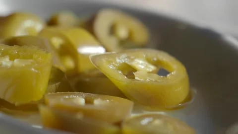 Close up slow motion of fresh pickled green jalapeo pepper slices in white .. Vidéo 331719755