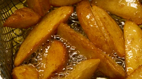 Close-up slow motion fried crispy potato wedges deep frying in oil. French fries Stock Footage 289702856