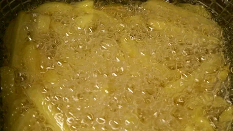 Close-up slow motion fried crispy potato wedges deep frying in oil. French fries Stockbeeldmateriaal 290294602