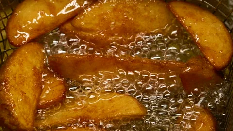 Close-up slow motion fried crispy potato wedges deep frying in oil. French fries Vídeos de archivo 292867382