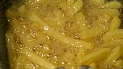 Close-up slow motion fried crispy potato wedges deep frying in oil. French fries Video stock 293431446