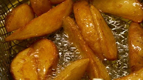 Close-up slow motion fried crispy potato wedges deep frying in oil. French fries Vídeos de archivo 294489560